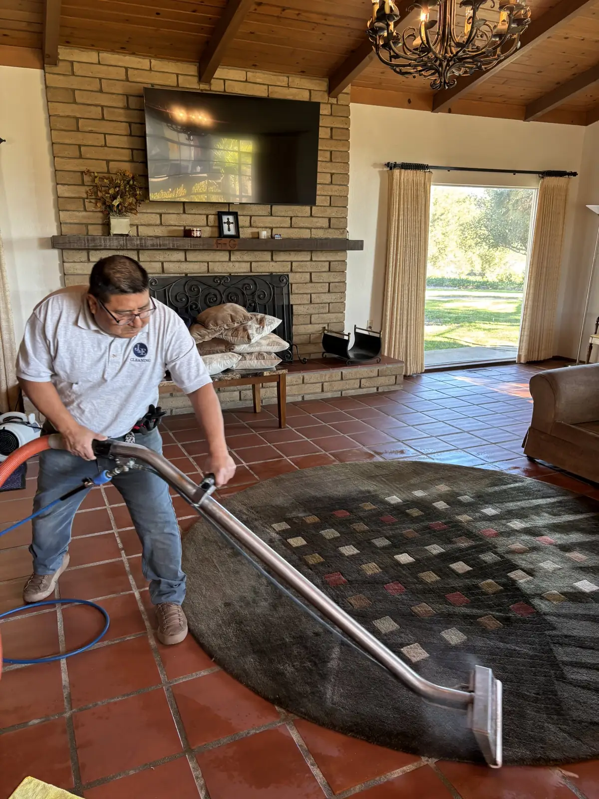J&E technician in a J&E uniform shirt cleaning an area rug