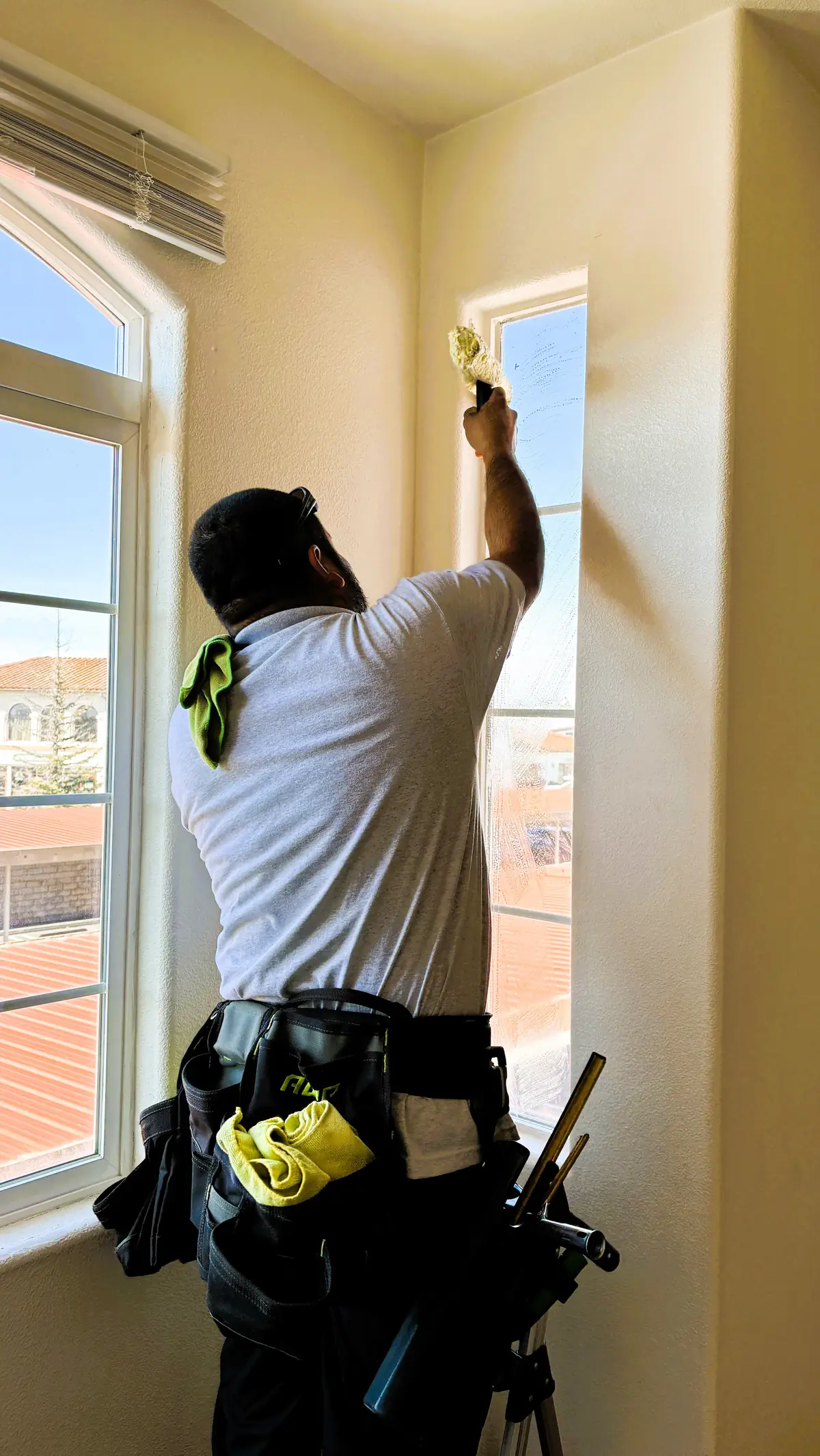 J&E window cleaner washing tall interior windows in a Central Coast home