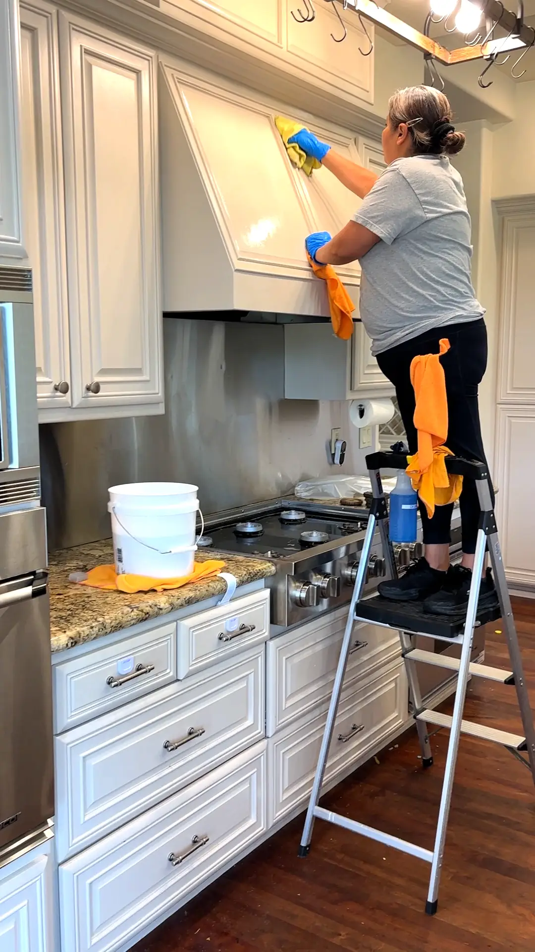 J&E house cleaner on a ladder cleaning a range hood