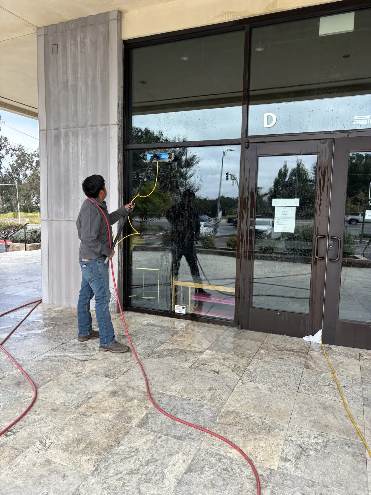J&E technician cleaning storefront glass with a water fed pole