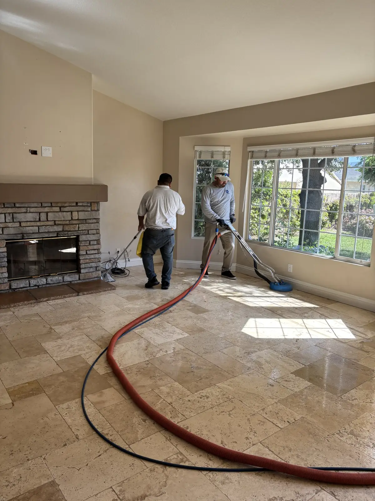 Two J&E technicians cleaning tile floors in a vacant home